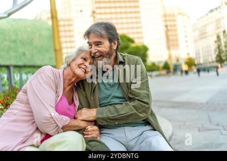 Ritratto con spazio per copiare una coppia matura seduto sulla panchina abbracciata in città Foto Stock