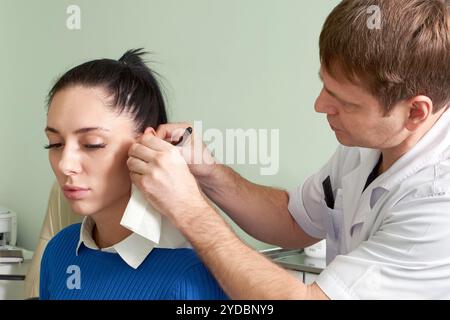 Attento medico maschile che fa l'esame dell'orecchio di Pretty Woman Foto Stock