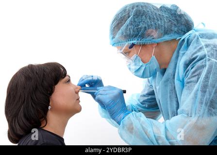 Medico in tuta protettiva che prende una gola e un tampone nasale da un paziente per verificare la possibile infezione da coronavirus o covid Foto Stock