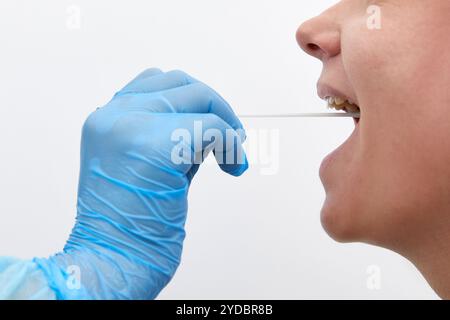 Medico in tuta protettiva che prende una gola e un tampone nasale da un paziente per verificare la possibile infezione da coronavirus o covid Foto Stock