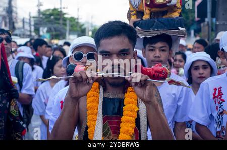 Un devoto cammina in processione dopo essere stato trafitto al Santuario Baan Tha Rua durante l'annuale Festival vegetariano nella città di Phuket. Il Festival ha generato 15 miliardi di Baht thailandesi nell'economia locale con oltre 400.000 visitatori. Foto Stock