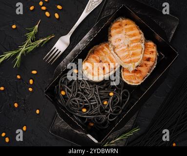 Salmone italiano servito su spaghetti neri Foto Stock