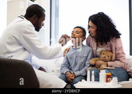 Medico che esamina un bambino malato con la madre che tiene l'orsacchiotto Foto Stock