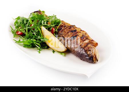 Pesce d'orata grigliato, limone, rucola su piatto bianco Foto Stock