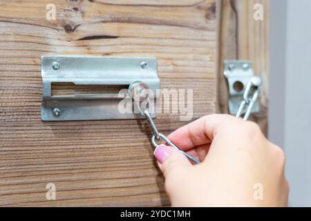 Primo piano della catena della porta di sicurezza che tiene la mano sulla porta di legno Foto Stock