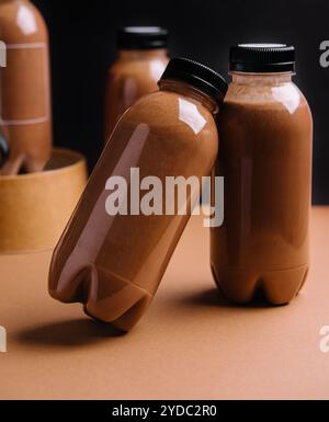 Frullati di cioccolato in bottiglie su sfondo nero e marrone Foto Stock