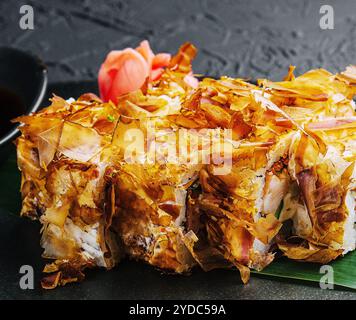 Panino di sushi bonito su un piatto scuro Foto Stock