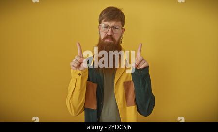 Un giovane uomo rosso barbuto si muove verso l'alto su uno sfondo giallo vibrante, raffigurando una presenza maschile adulta sicura. Foto Stock
