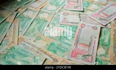 Banconote in dirham sparse degli emirati arabi uniti che mostrano vari tagli di valuta emiratina, tra cui dieci, cinquanta e cento dirham, che rappresentano l'unità Foto Stock