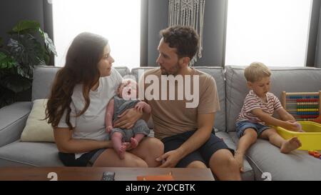 Famiglia con madre, padre e due ragazzi seduti in salotto, che si impegnano in un momento di amore a casa Foto Stock