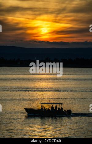 Sicilia, Italia. 25 ottobre 2024. Le barche turistiche passano il sole al tramonto nel porto - Autunno a Siracusa, Sicilia, Italia. Crediti: Guy Bell/Alamy Live News Foto Stock