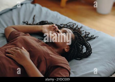 Donna sorridente sdraiata sul letto e rilassante Foto Stock