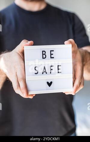 L'uomo che tiene la scatola luminosa con il testo sia al sicuro in mano Foto Stock