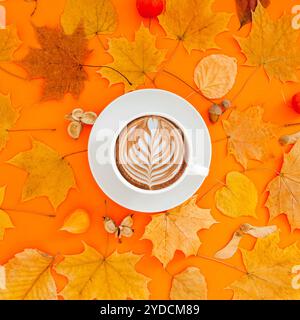 Autunno piatto composizione laici con foglie secche ghirlanda di telaio e caffè latte cup sul bold orange Colore di sfondo. Creative autunno, ringraziamento, caduta, ha Foto Stock