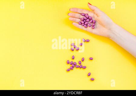 Donna con mano in mano pillole viola manciata Foto Stock