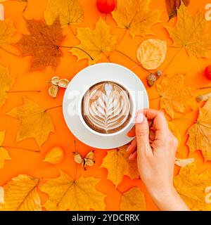 Tazza di caffè latte in foglie autunnali asciutte con struttura a corona Foto Stock