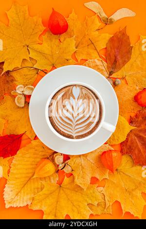 Autunno piatto composizione laici con foglie secche ghirlanda di telaio e caffè latte cup sul bold orange Colore di sfondo. Creative autunno, ringraziamento, caduta, ha Foto Stock