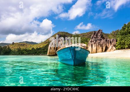 Vecchia barca da pesca sulla spiaggia tropicale dell'isola Curieuse alle Seychelles Foto Stock