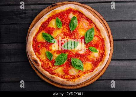 Pizza Margherita su sfondo in legno nero Foto Stock