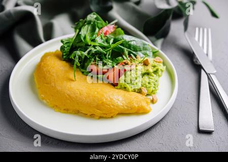 Omelette servita con purea di avocado e pomodori ciliegini Foto Stock