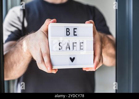 L'uomo che tiene la scatola luminosa con il testo sia al sicuro in mano Foto Stock