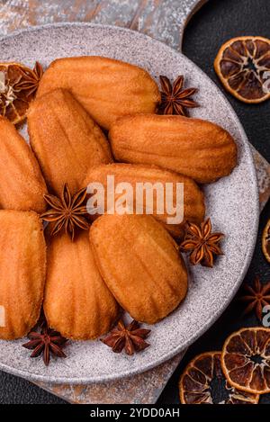 Tradizionali biscotti francesi madeleine con sapore di nocciola su sfondo di cemento scuro Foto Stock