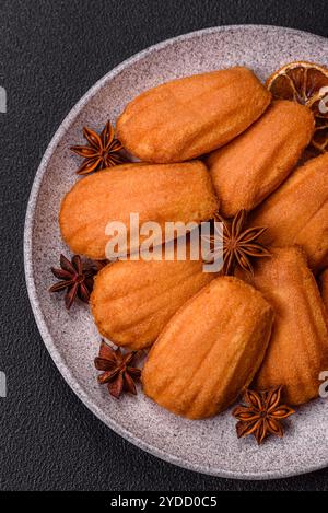 Tradizionali biscotti francesi madeleine con sapore di nocciola su sfondo di cemento scuro Foto Stock