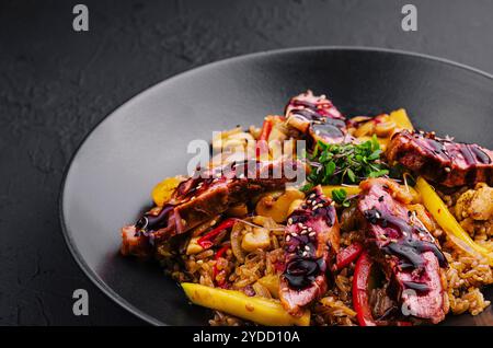 Riso fritto cinese con manzo su piatto nero Foto Stock