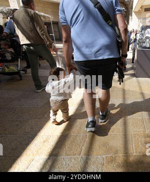 Un uomo porta un fucile mentre cammina attraverso il Mamilla Mall a Gerusalemme, Israele, il 20 ottobre 2024. Foto di Raquel G. Frohlich. Foto Stock