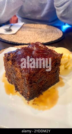 Primo piano di budino di toffee appiccicoso, un tradizionale dessert scozzese, servito con una ricca salsa di toffee e gelato alla vaniglia Foto Stock