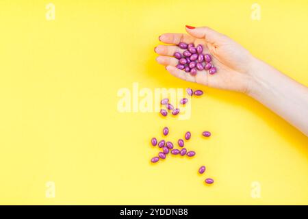 Donna con mano in mano pillole viola manciata Foto Stock