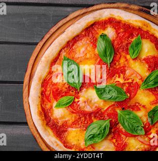 Pizza Margherita su sfondo in legno nero Foto Stock