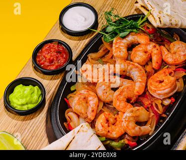 Gamberi grandi fritti con cipolle e peperoni in una padella Foto Stock