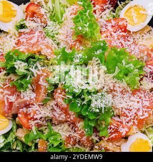 Insalata con salmone, lattuga, uova sode, pomodori ciliegini e parmigiano Foto Stock