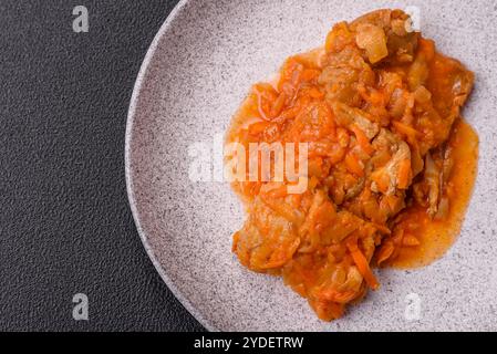 Affettare il pesce in salsa di pomodoro con sale e spezie su uno sfondo di cemento scuro Foto Stock