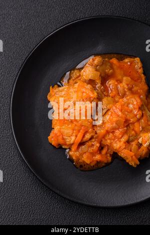 Affettare il pesce in salsa di pomodoro con sale e spezie su uno sfondo di cemento scuro Foto Stock