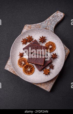 Caramelle rettangolari al cioccolato con mousse e waffle su sfondo di cemento scuro Foto Stock