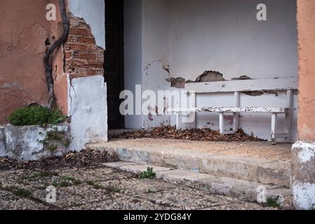 Panca di legno bianco all'ingresso di un edificio in rovina Foto Stock
