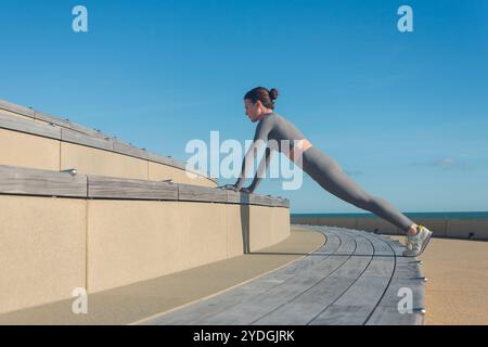 una donna sportiva che fa un asse, spinge l'esercizio su una panchina Foto Stock