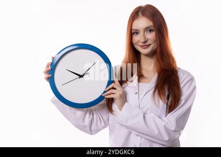 Una donna tiene in mano un orologio mentre indossa un camice da laboratorio in un ambiente professionale ufficiale Foto Stock