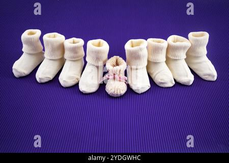 Giornata mondiale della prematurità. Nove calze bianche su sfondo viola, con un berretto rosa al centro. Foto Stock