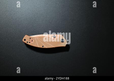 coltello pieghevole marrone su sfondo nero Foto Stock