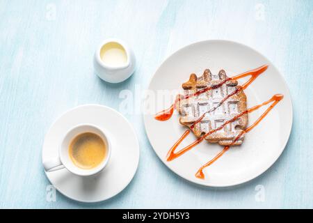 Una tazza di caffè espresso e waffle belgi con gelato e ripieno di fragole su un piatto bianco e latte. Colazione deliziosa e salutare. Alta qualità Foto Stock