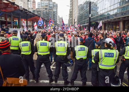 Londra, Regno Unito. 26 ottobre 2024. Gli agenti di polizia formano un cordone a Victoria Street mentre migliaia di manifestanti marciano in solidarietà con la figura di estrema destra Tommy Robinson, che è stato arrestato in base al Terrorism Act. Credito: SOPA Images Limited/Alamy Live News Foto Stock