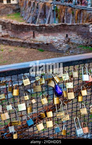 Lucchetti d'amore attaccati a una recinzione che domina le antiche rovine del Ludus Magnus, Roma, Italia. Foto Stock