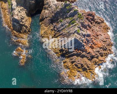 Vista aerea di un aspro promontorio costiero con geologia vulcanica a Eden, sulla costa meridionale del nuovo Galles del Sud, Australia. Foto Stock