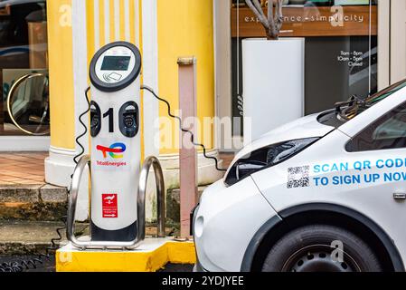 Un'auto elettrica a noleggio collegata a un punto di ricarica Total Energies EV nel centro di Singapore Foto Stock