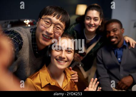 Ritratto di una donna gioiosa che sorride alla fotocamera mentre scatta selfie con quattro amici allegri Foto Stock