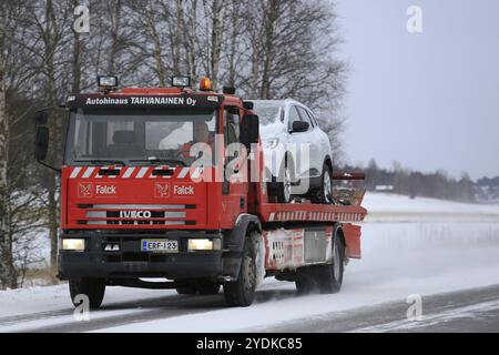 SALO, FINLANDIA, 7 GENNAIO 2017: Il carro trainato rosso Iveco traina un'auto lungo la strada in una giornata fredda in inverno. Le temperature al di sotto dello zero possono causare molti problemi meccanici Foto Stock