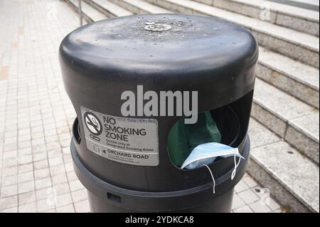 02.04.2020, Singapore, Repubblica di Singapore, Asia, Una maschera scartata è appesa in un bidone della spazzatura fuori da una stazione della metropolitana nel centro della città, Asia Foto Stock